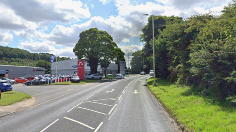 The A64 with Stoneacre car showroom car room to the left. To the right of Stoneacre there are three lanes, one going out of Scarborough, the middle lane turning into Stoneacre car showroom car park and the far lane going into Scarborough.