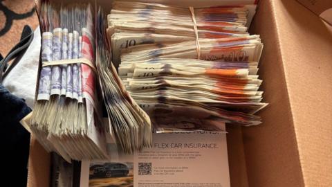Bundles of cash in a brown shoebox, including £10, £20 and £50 notes.