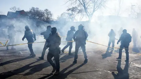 Federal agents gather amid tear gas during scuffles at the scene of a shooting involving federal immigration agents in Minneapolis