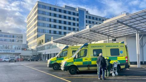 Ambulances parked outside a large white hospital building.