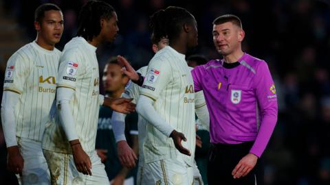 Referee Ollie Yates talks with Kgaogelo Chauke of Burton Albion