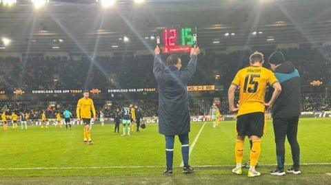 Ross Bennett holding the substitute board at Molineux  