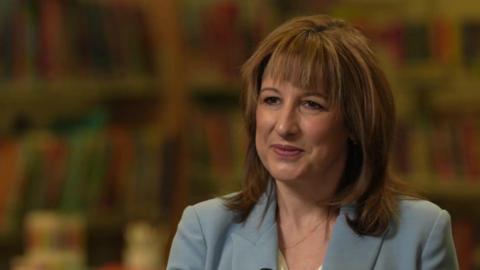 Chancellor Rachel Reeves, sitting down being interviewed, wearing a light blue suit jacket
