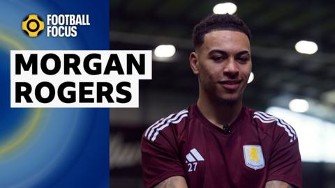 Morgan Rogers smiles in a maroon and light blue Aston Villa training top