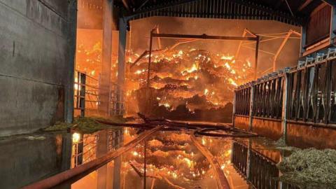 A large amount of hay on fire in a barn