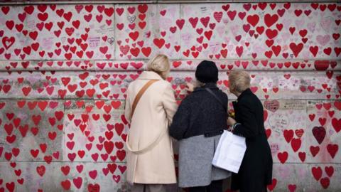 Women looking at Covid memorial wall