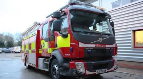 A red and yellow fire engine parked in front of a metal building.