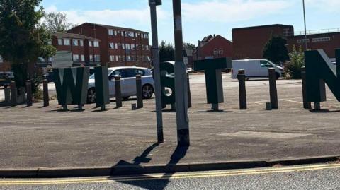 A sign for 'Wigston' missing the letters 'G' and 'O'. 