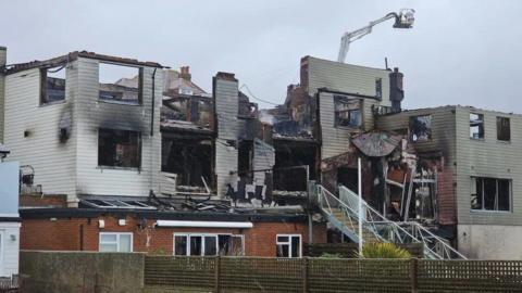 Shell of pub building with numerous burnt out windows on three levels no roof and blackened interior