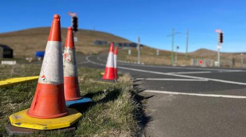 Traffic cones on the side of the road at the Bungalow on the Mountain Road with Snaefell Mountain is in the background.
