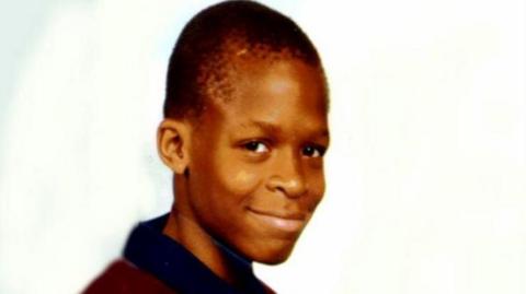 Damilola Taylor, 10, in a burgundy and black shirt.