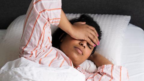 A woman lays in bed struggling to sleep.