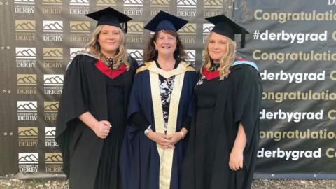 Jessica and Lucy Sheldon in their black gowns with red trim and Jayne Leverton in a navy gown with gold trim. All three are wearing black mortarboards