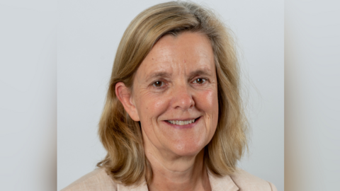 A headshot of Tandridge District Council leader Catherine Sayer, who has shoulder length fair hair and is wearing a beige jacket. She is only visible from the shoulders up. 