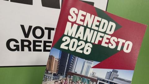 Close up of the cover of Wales Green Party's manifesto book next to a green backdrop.