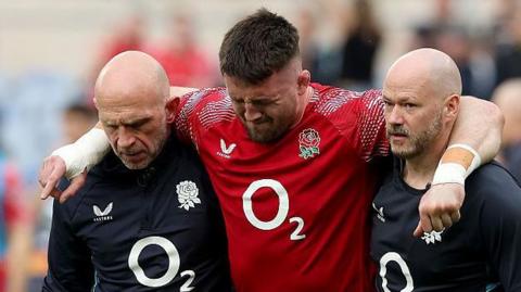 Tom Curry is helped off the pitch after suffering an injury