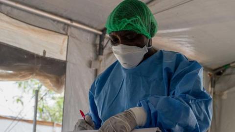 An image of a doctor wearing a white face mask and a blue medical apron.