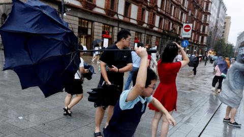 A person holds an inverted umbrella as winds intensify ahead of the arrival of Typhoon Dolphin in Shanghai, China.