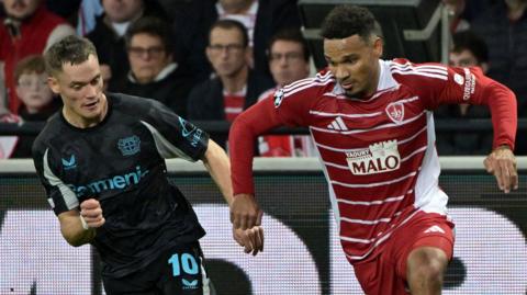 Brest's French defender #07 Kenny Lala (R) runs with the ball ahead of Bayer Leverkusen's German midfielder #10 Florian Wirtz (L)