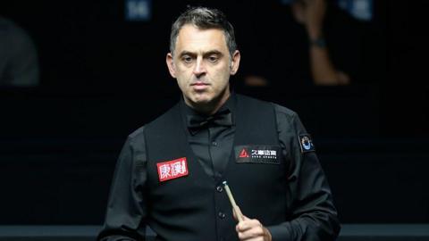 Ronnie O'Sullivan holds a snooker cue