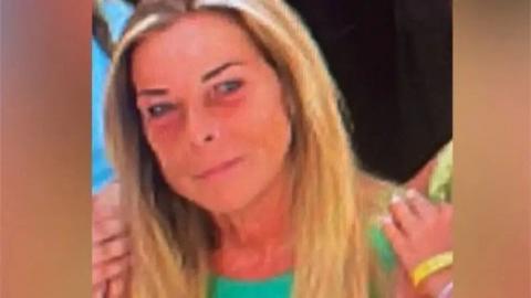 A woman with long blonde hair, aged around 60. She is wearing a green top and smiling into the camera.