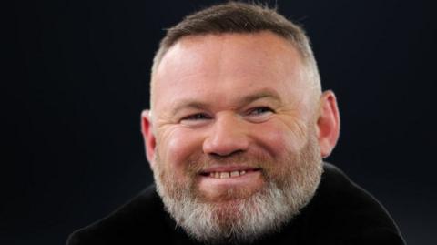 Wayne Rooney smiling against a black background