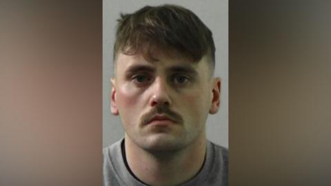 Mugshot of James. He has a neat brown moustache and short brown hair