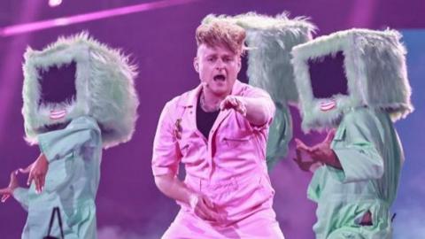 Look Mum No Computer on stage in a pink jumpsuit