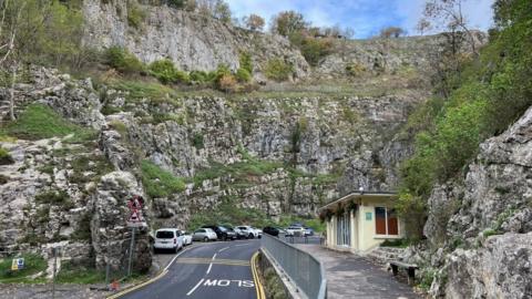 Cheddar Gorge with cars parked along the road with the rocks above