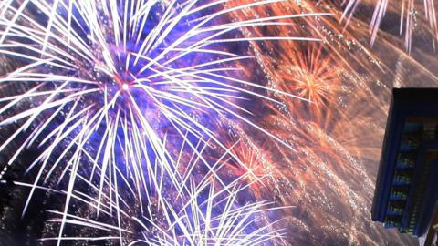 Bright purple and red fireworks exploding in the sky.