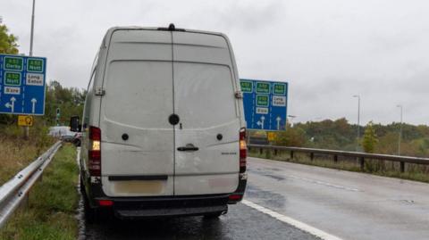 A van with the number plate blurred on the side of the M1