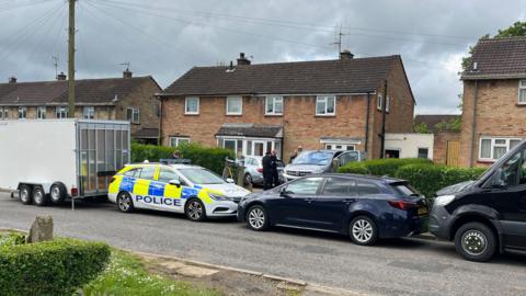 Police car as well as other cars parked on a residential street in Caddington. 