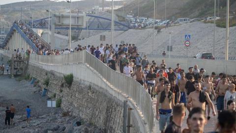 Dozens of migrants walking on a coastal path 