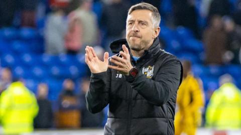 Port Vale manager Jon Brady claps the club's fans at the Cardiff City stadium after their relegation from League One was confirmed