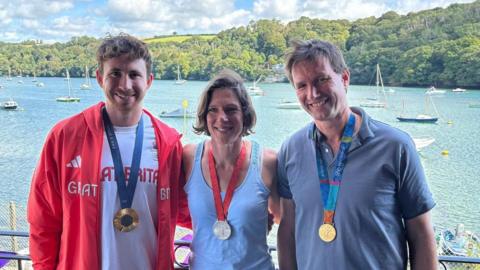 Morgan Bolding is pictured on the left wearing his gold medal and red Team GB jacket while Annie Vernon is positioned in the centre with her silver medal and Ed Coode is to her right with his gold medal.