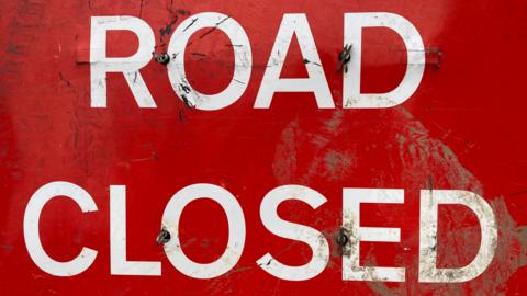 A red 'road closed' traffic sign.