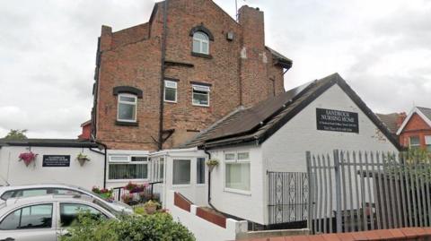 Sandrock Nursing ˿, a whitewashed bungalow style building connected to a large three storey property