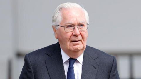 Lord Mervyn King in a dark grey suit and blue tie