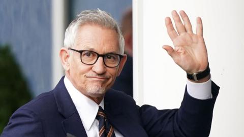 Gary Lineker wearing a suit and waving outside