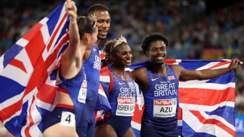 Jeremiah Azu, Dina Asher-Smith, Amy Hunt, and Zharnel Hughes of Team Great Britain pose for a photo with their national flags