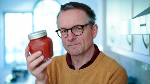 Michael Mosley holding a red jar.