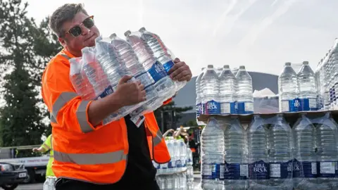 Man in high-vis holding water bottles