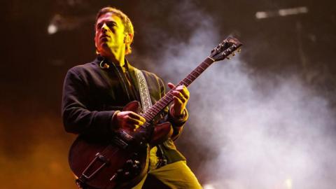 Caleb Followill, singer of the US band Kings of Leon, performs onstage at the Estéreo Picnic Festival in Bogotá on March 21, 2024. He's in a black jacket with a brown guitar in hand - smoke can be seen behind him