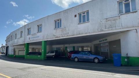 The white garage on St Clement's Road, St Helier, which has open bays with cars inside them and a row of windows on the second storey