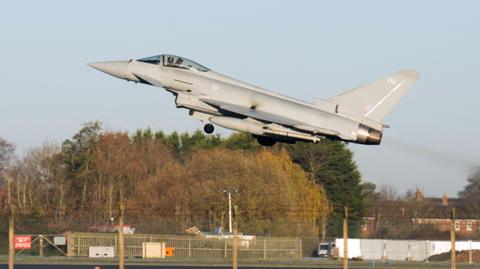 A Typhoon taking off from RAF Coningsby in Linconshire. The sky is blue.