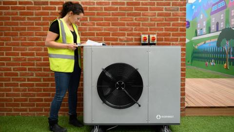 A project engineer checks the paperwork for the installation of a Daikin 7KW heat pump on a model house within the Octopus Energy training facility on November 02, 2021 in Slough, England.