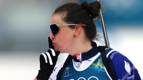 French biathlete Julia Simon holds a finger to her mouth after winning Olympic gold