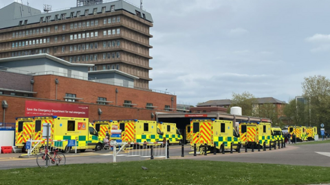 Around nine ambulances are seen queuing up outside the A&E department at Gloucestershire Royal Hospital on a clear day