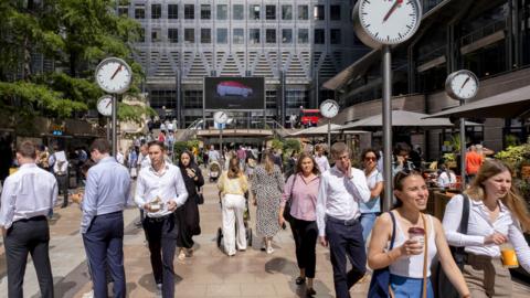People walk around Canary Wharf in London