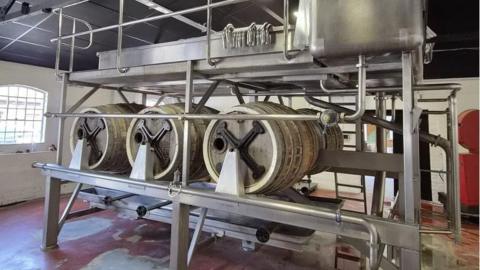 A stainless steel brewing mechanism involving six large barrels under metal equipment